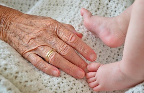 старческая рука и ножки младенца. фото