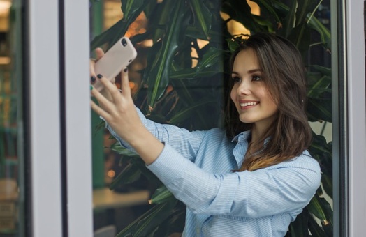Молодая женщина смотрит в камеру смартфона. фото