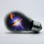 Лампочка с нарисованной галактикой. иллюстрация
