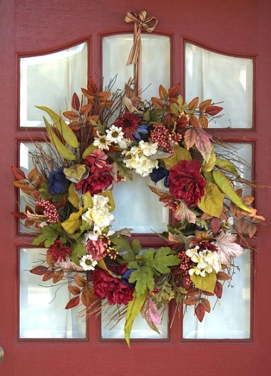 Висящий на двери венок из цветов и листвы. иллюстрация