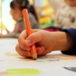 Оранжевый карандаш в детской руке. фото