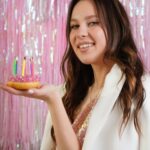 Девушка держит в ладони пирожное со свечкам. фото