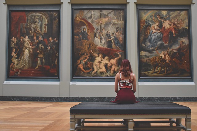 Девушка на скамье смотрит на выставленные картины. фото